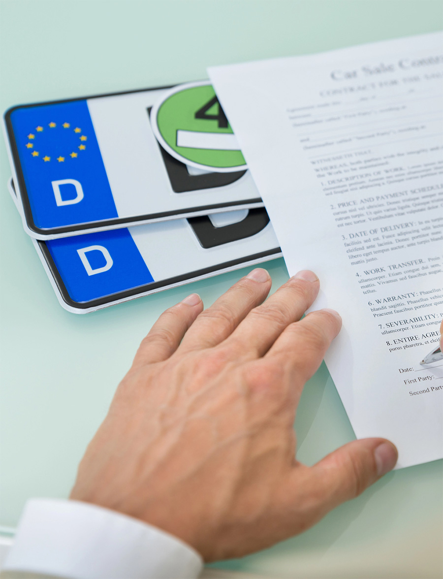 Hand reviewing car ownership documents and license plates
