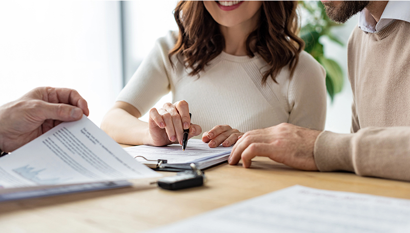 Couple signing a home insurance policy document with an agent